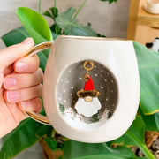 White mug with gold handle and rim, Father Christmas figure in a snowy circle