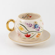 Porcelain coffee cup and saucer set with botanical flowers, gold handle, and blue eye
