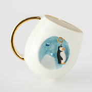 Porcelain mug with penguin graphic, blue wash, and gold handle and inner rim
