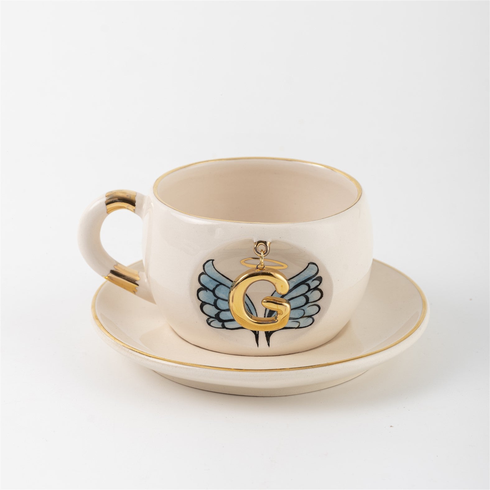 Ceramic angel-wing letter mug with blue wings and gold G, on matching saucer