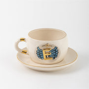 Ceramic angel-wing letter mug with blue wings and gold E, on matching saucer