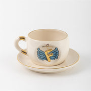 Ceramic angel-wing letter mug with blue wings and gold F, on matching saucer