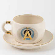 Tea mug with saucer, white ceramic, gold trim, blue medallion letter A