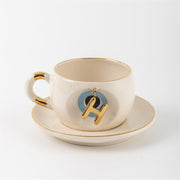 Tea mug with saucer, white ceramic, gold trim, blue medallion letter H