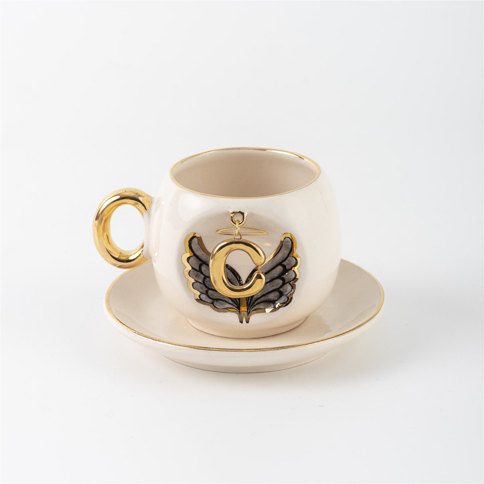 Porcelain cup and saucer with gold handle, black angel wing motif, letter C