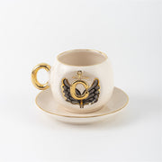 Porcelain cup and saucer with gold handle, black angel wing motif, letter C