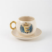 Ceramic coffee cup and saucer with gold E, blue angel wings, and curved gold handle