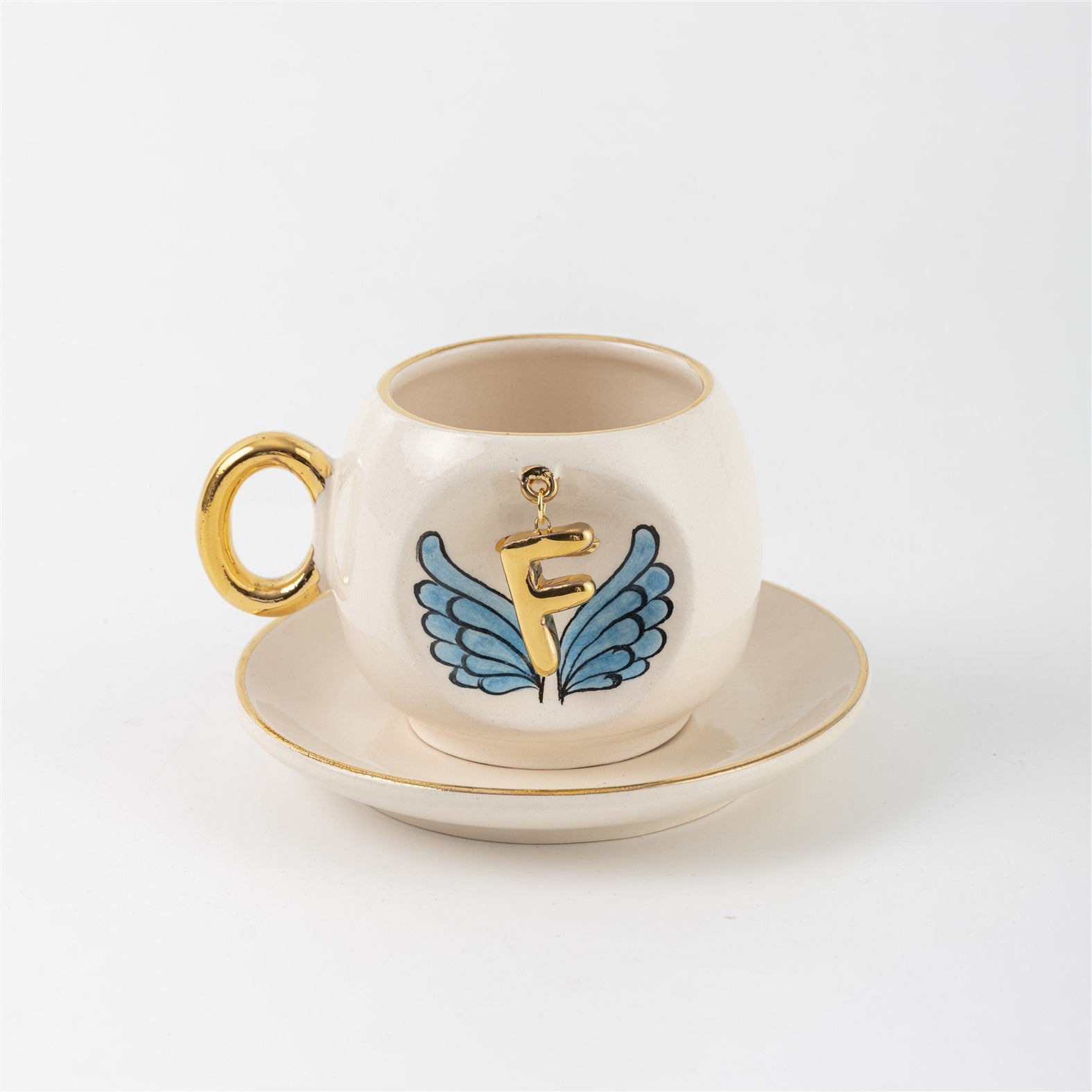 Ceramic coffee cup and saucer with gold F, blue angel wings, and curved gold handle