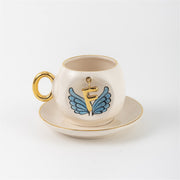 Ceramic coffee cup and saucer with gold F, blue angel wings, and curved gold handle