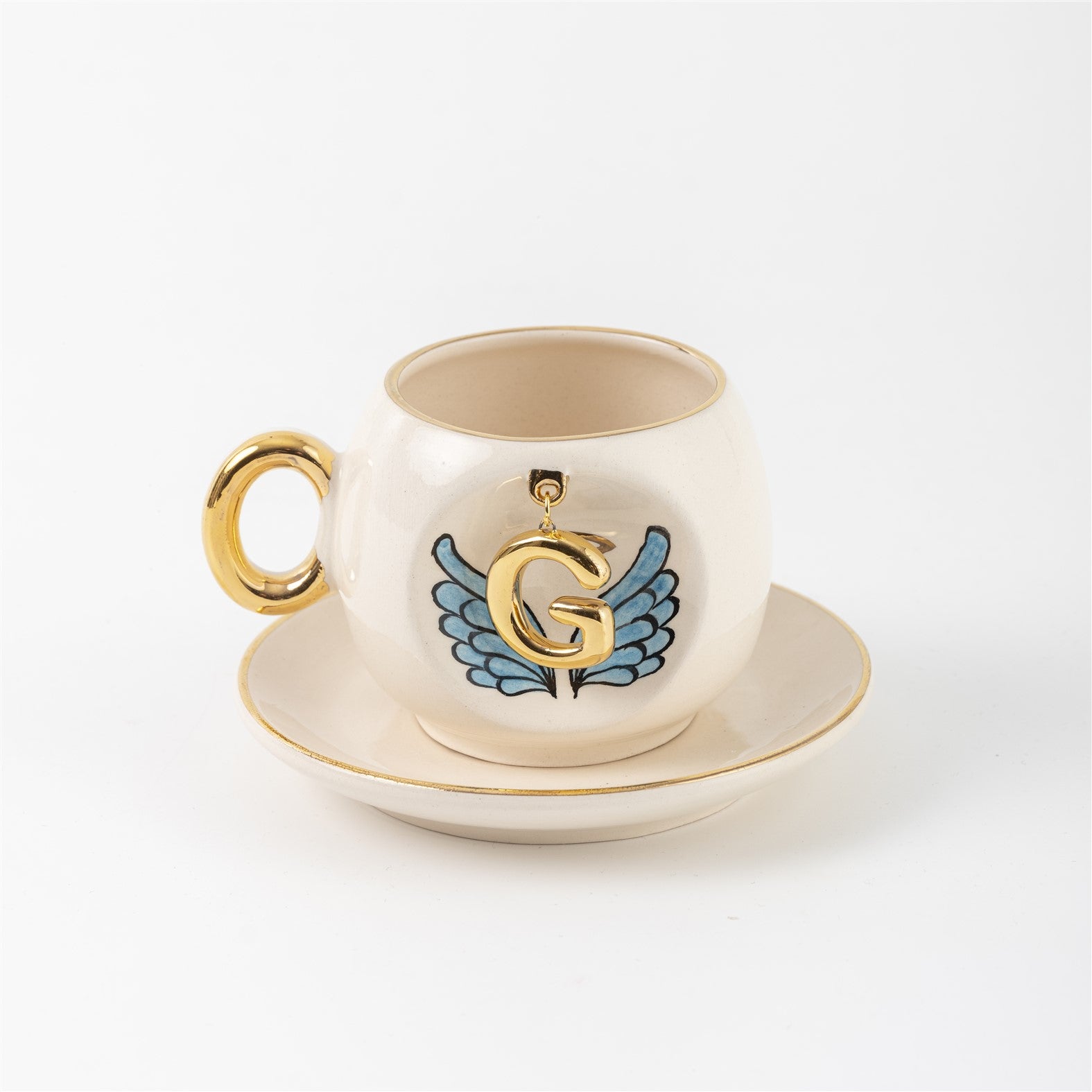 Ceramic coffee cup and saucer with gold G, blue angel wings, and curved gold handle