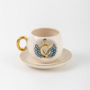 Ceramic coffee cup and saucer with gold C, blue angel wings, and curved gold handle