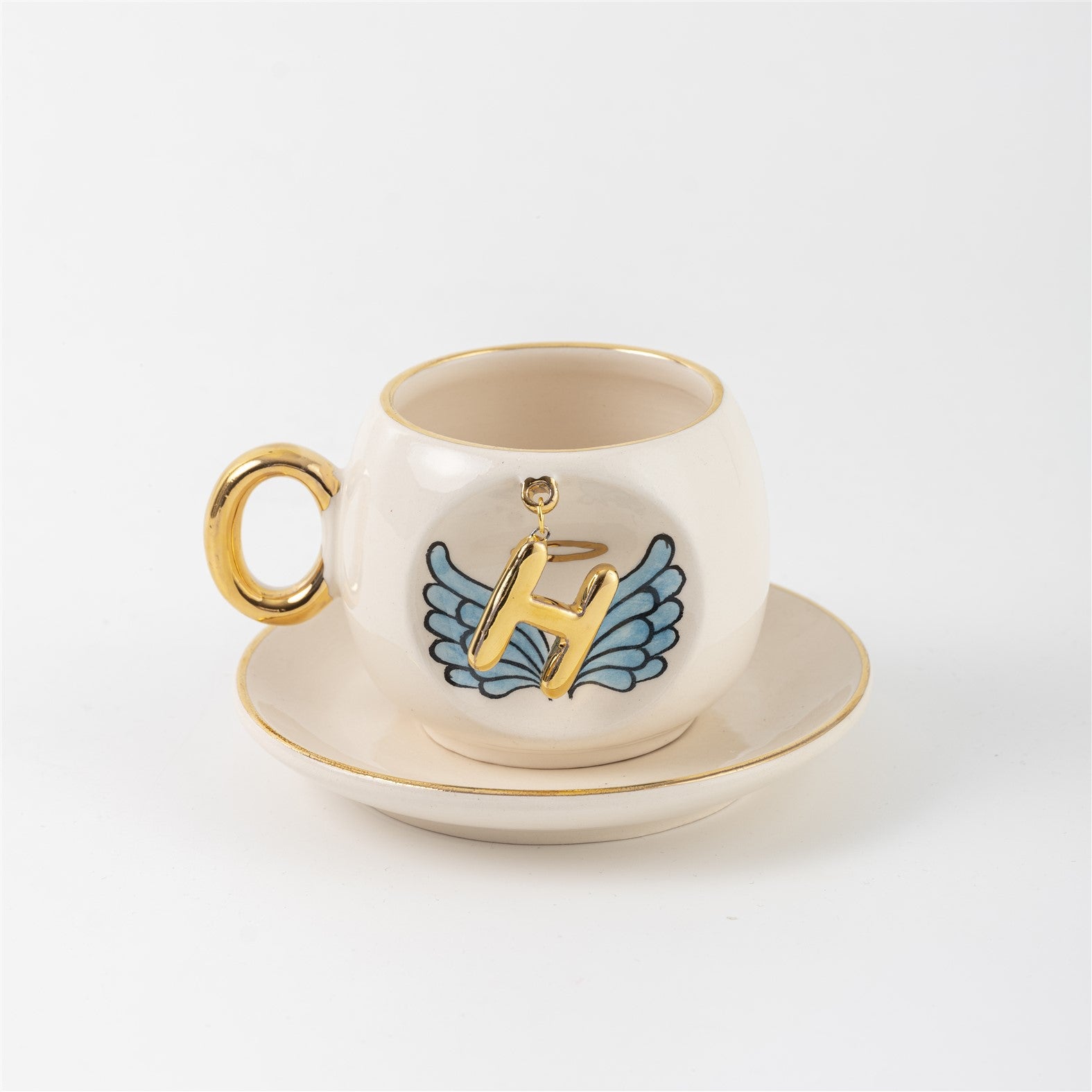 Ceramic coffee cup and saucer with gold H, blue angel wings, and curved gold handle