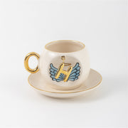 Ceramic coffee cup and saucer with gold H, blue angel wings, and curved gold handle