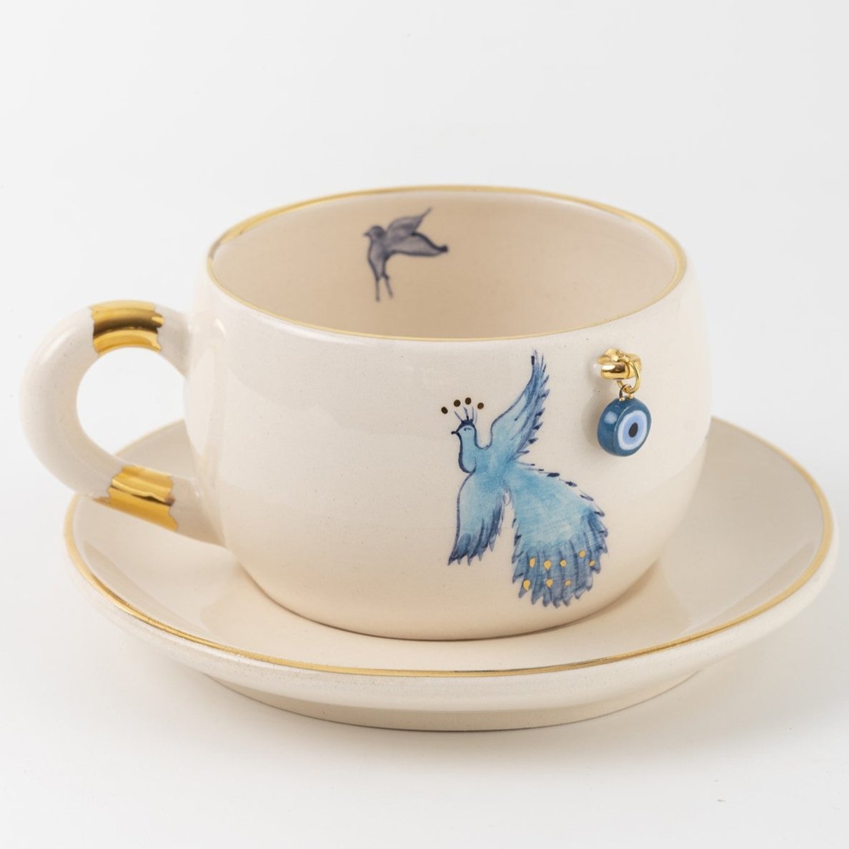 Porcelain mug and saucer with blue bird and eye charm, gold handle accents
