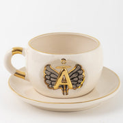 Porcelain mug and saucer with gold-trim angel wing letter emblem