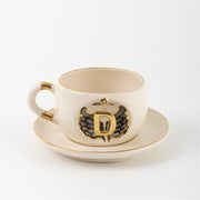 Porcelain mug and saucer with angel wing badge and gold letter V, cream base