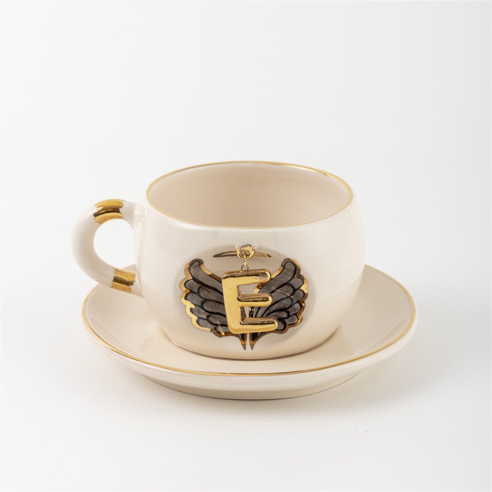 Porcelain mug and saucer with angel wing badge and gold letter E, cream base