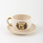 Porcelain mug and saucer with angel wing badge and gold letter G, cream base