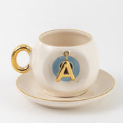 Ceramic Turkish coffee cup and saucer with gold handle, blue letter A charm