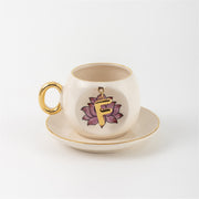 Ceramic coffee cup and saucer with gold handle, lotus letter F emblem on front
