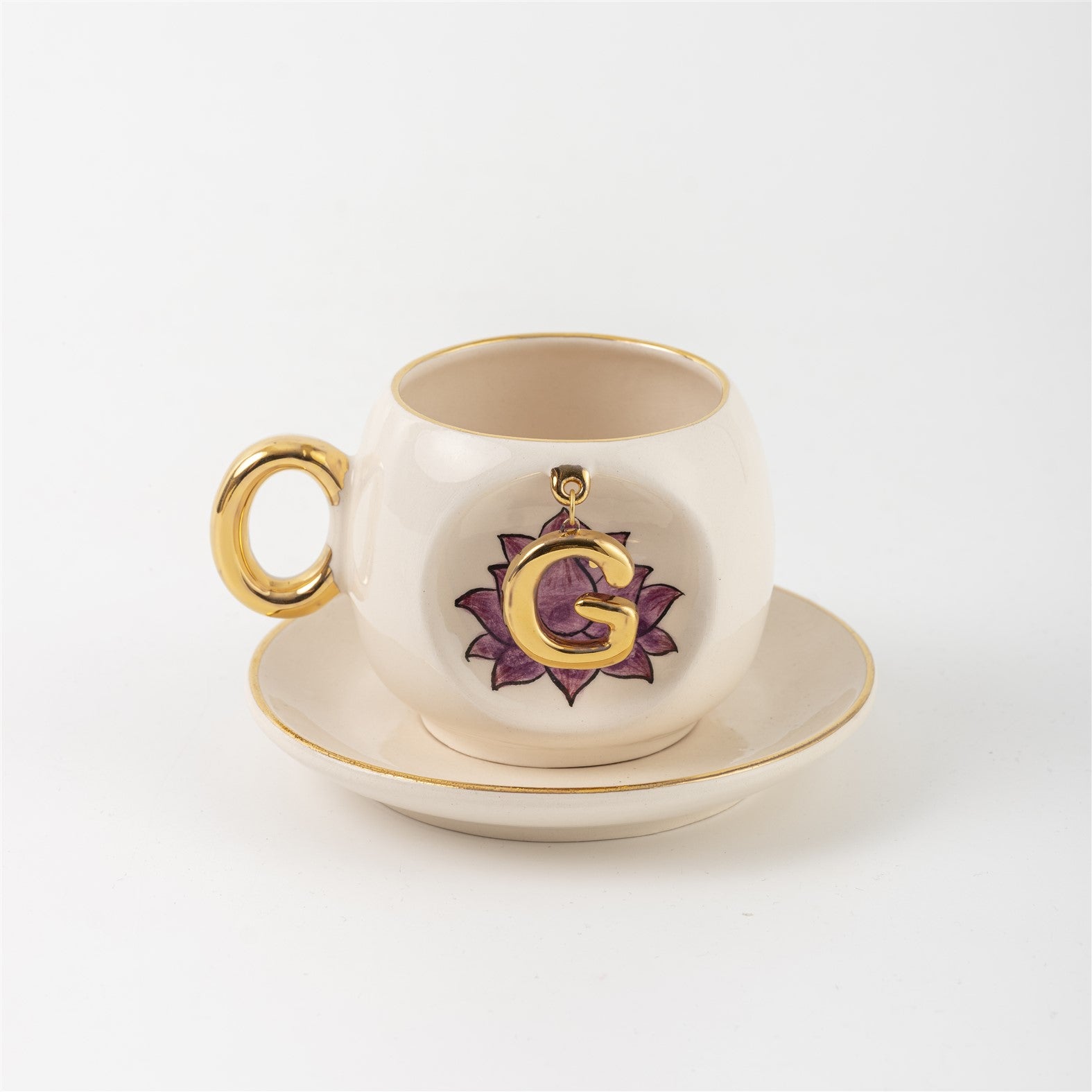 Ceramic coffee cup and saucer with gold handle, lotus letter G emblem on front