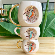 Kingfisher mug set stacked, white ceramic with gold handles and round bird illustration