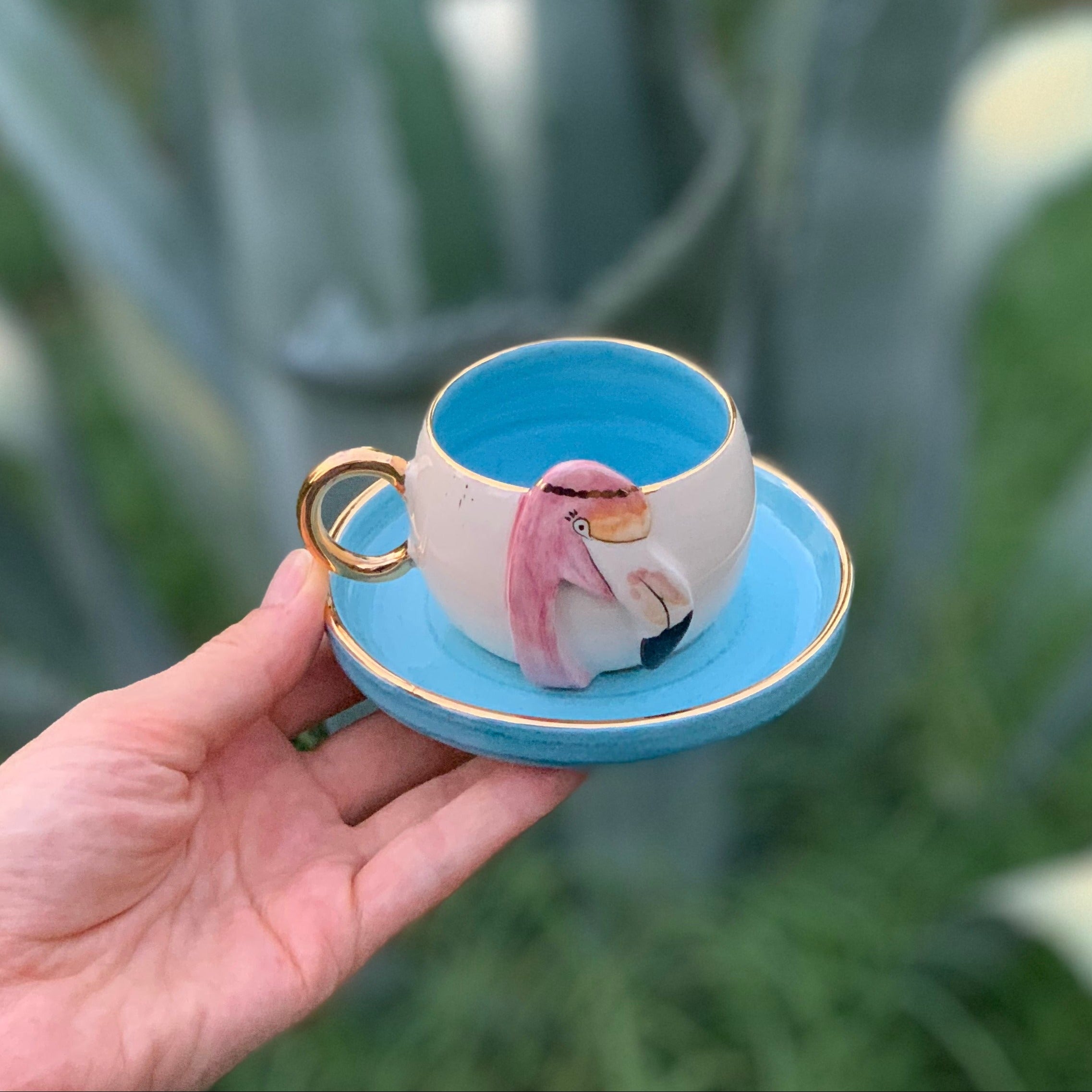 Blue ceramic flamingo coffee cup with matching saucer and gold handle, pink bird print